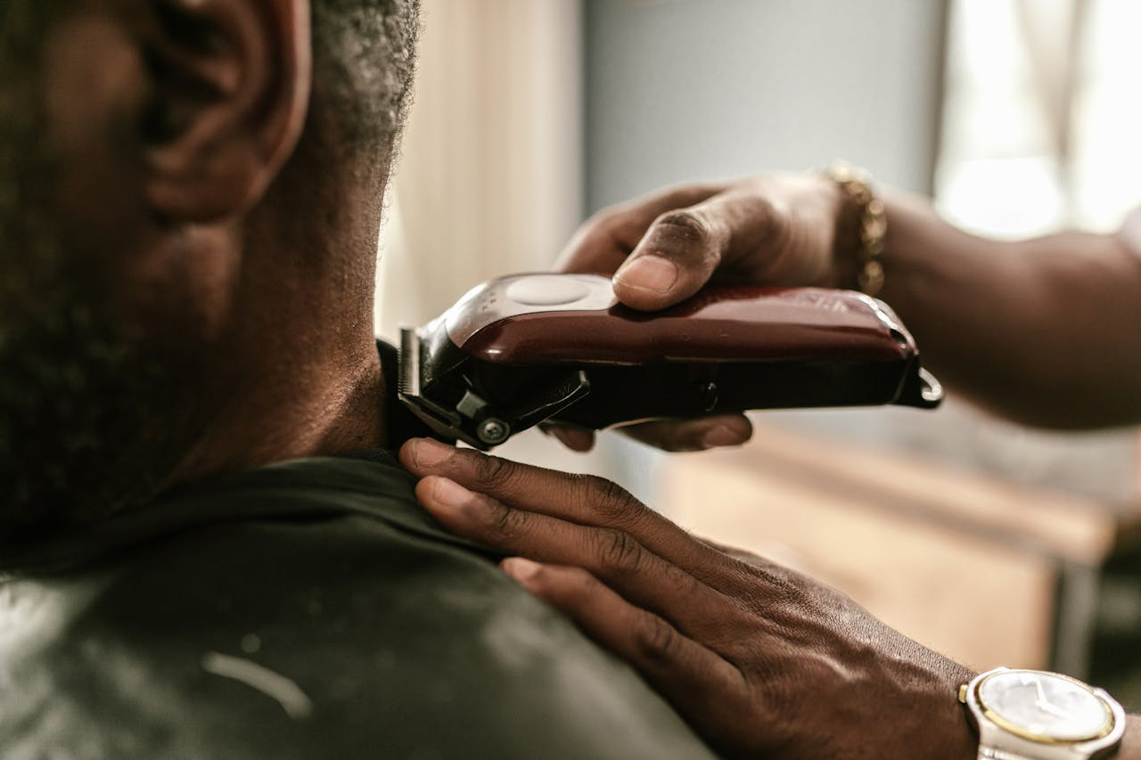Barber using clippers to trim a clients hair in a barbershop setting.